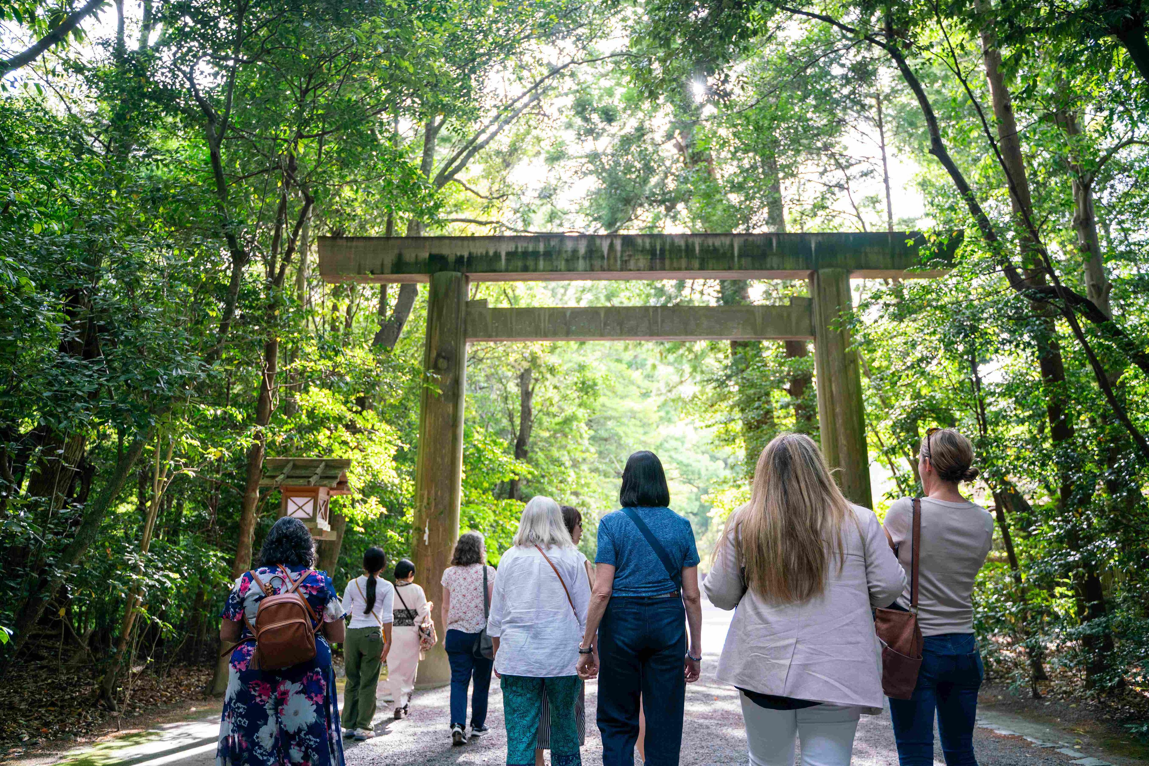 A photo of KonMari Consultants walking through stunning greenery under a Japanese torii gate