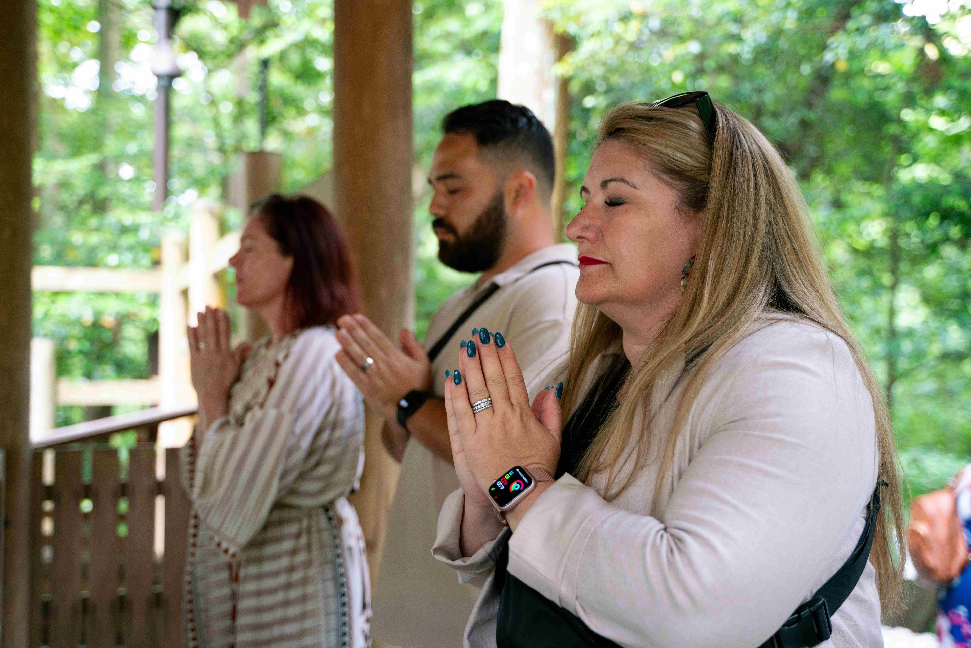 KonMari Consultants close their eyes and put their hands together at a shrine.